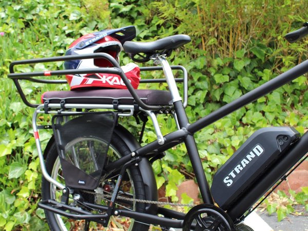 A Strand-branded helmet resting on the rear rack of a cargo e-bike.