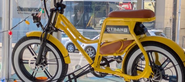 A yellow Strand Super Moto e-bike in the shop window on Pacific Coast Highway.
