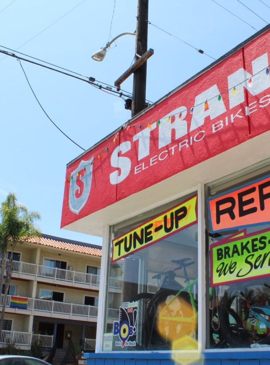 The red Strand Electric Bikes storefront sign on Pacific Coast Highway, Hermosa Beach.